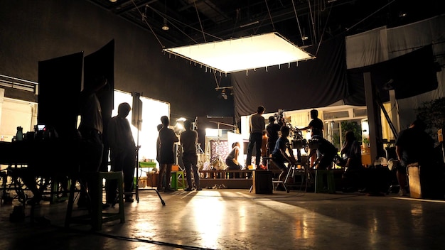 Behind the scenes or the making of film video production and movie crew team working in silhouette of camera and equipment set in studio