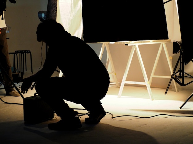 Foto dietro le quinte delle riprese di una produzione video in uno studio con un piccolo set di apparecchiature di illuminazione professionale.
