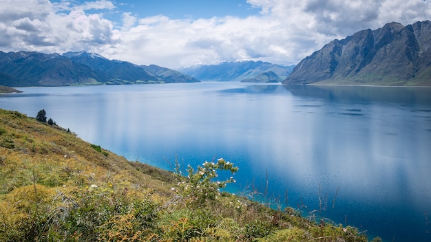Живописное альпийское озеро, окруженное горами, снято в солнечный день на озере хавеа, новая зеландия