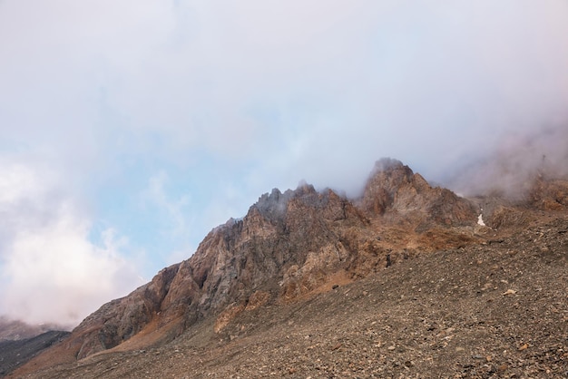 Paesaggio alpino panoramico con montagne rocciose in fitte nuvole basse alla luce del sole mattutino scenario di montagna colorato con rocce affilate tra spesse nuvole basse splendida vista sulle alte montagne rocciose in condizioni di scarsa nuvolosità