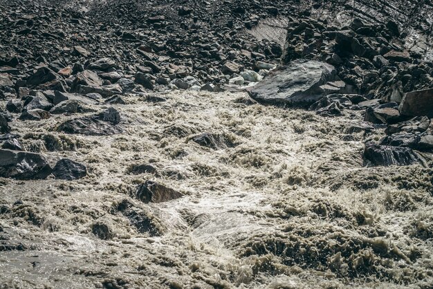 Scenic highlands landscape of powerful mountain river beginning from glacier among large moraines.