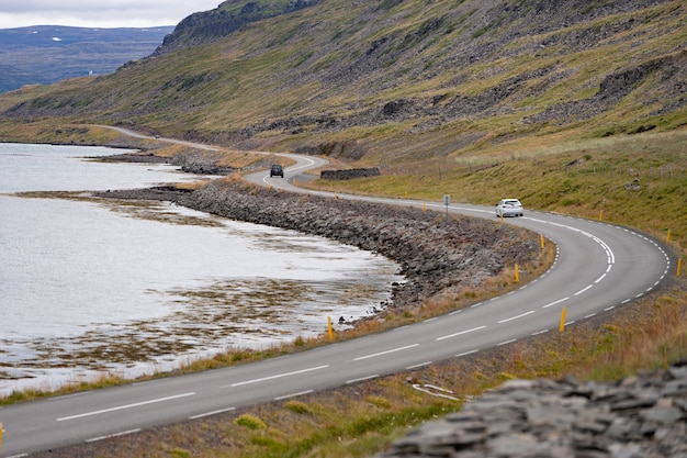 Scenic landscape with car driving by beautiful road, fjord and coastline from Iceland Westfjord.