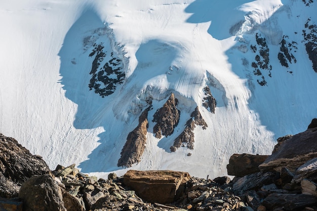 Scenic landscape with snow mountains and rocks in sunlight Awesome scenery with snowy rocky mountain wall Beautiful alpine view to mountain tops and moraines at very high altitude sky in sunny day