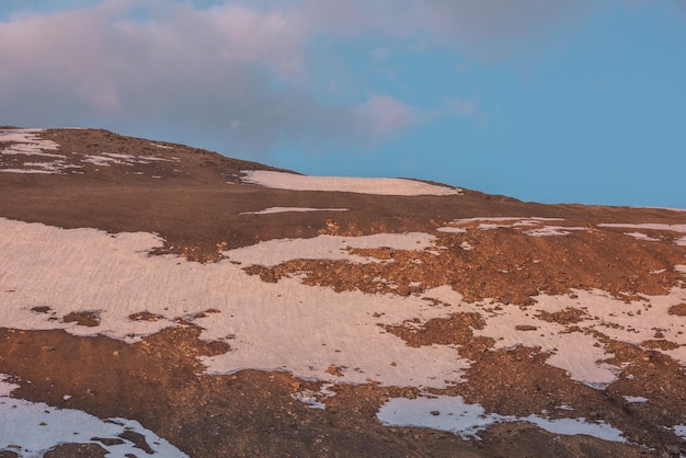 Фото Красивый утренний пейзаж с солнечным золотым горой со снегом под облаками в голубом небе на восходе солнца красивый пейзаж с высокой горой со снегом в золотом солнце под облачным небом в цветах восхода солнца