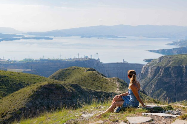 写真 湖辺の美しい青いドレスを着た1人の女性と美しい山の風景