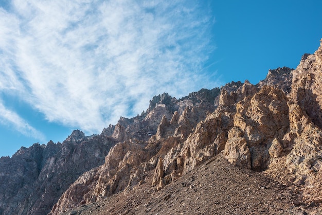 Фото Живописный горный пейзаж с острыми скалами под перистыми облаками в солнечный день красочные пейзажи с залитыми золотым солнцем острыми скалистыми горами высокие скалистые горы в золотом солнечном свете под плывущими облаками