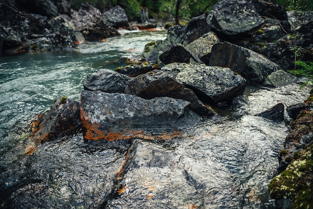 Fondo scenico della natura del flusso d'acqua limpida turchese tra rocce con muschi e licheni. atmosferico paesaggio montano con pietre di muschio in un torrente di montagna trasparente. bellissimo ruscello di montagna.