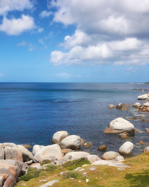 Scenic ocean view of beach with rocks or boulders and sea water washing onto shore during peaceful summer vacation in tropical resort and island overseas Rough texture and detail of rocky coastline