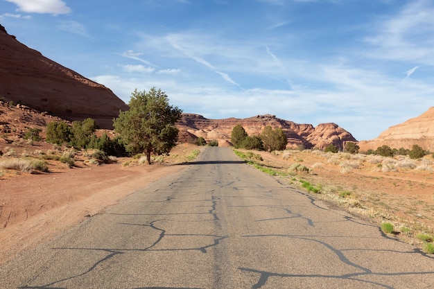 Scenic road in the dry desert with red rocky mountains in background