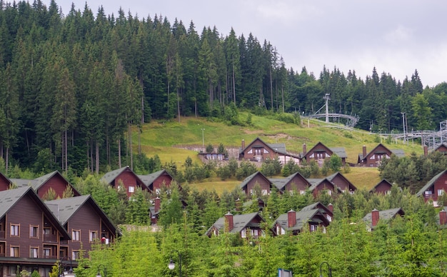 Scenic summer view of winter mountain ski resort with house cottages with forest and skiing slope in Bukovel Ukraine