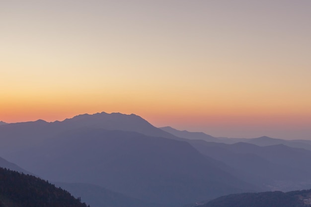 Un tramonto panoramico in montagna con la luce del sole bella luce paesaggio estivo serale in una valle con fiori di erba cielo orizzonte escursioni e trekking