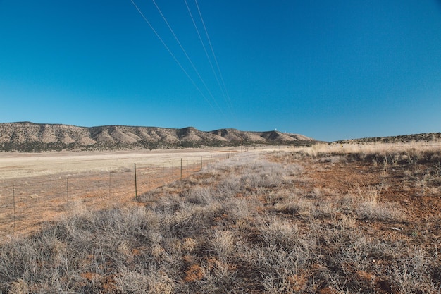 Scenic view of arid landscape against clear blue sky during sunny day