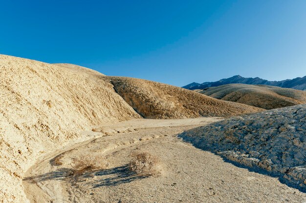 Scenic view of arid landscape against clear blue sky