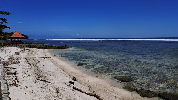 Scenic view of beach against clear blue sky