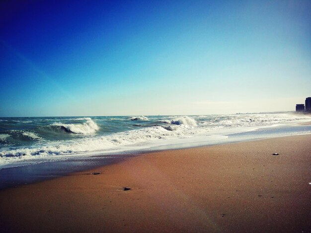 Scenic view of beach against clear blue sky