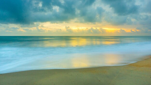 Photo scenic view of beach against cloudy sky during sunset