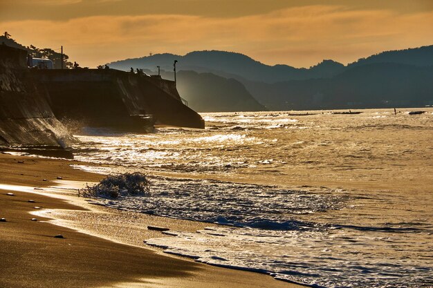 Photo scenic view of beach against dramatic sky during sunrise