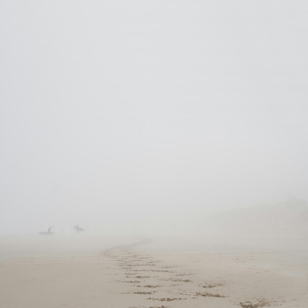 Photo scenic view of beach against sky during foggy weather