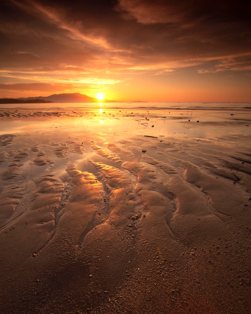 Photo scenic view of beach against sky during sunset