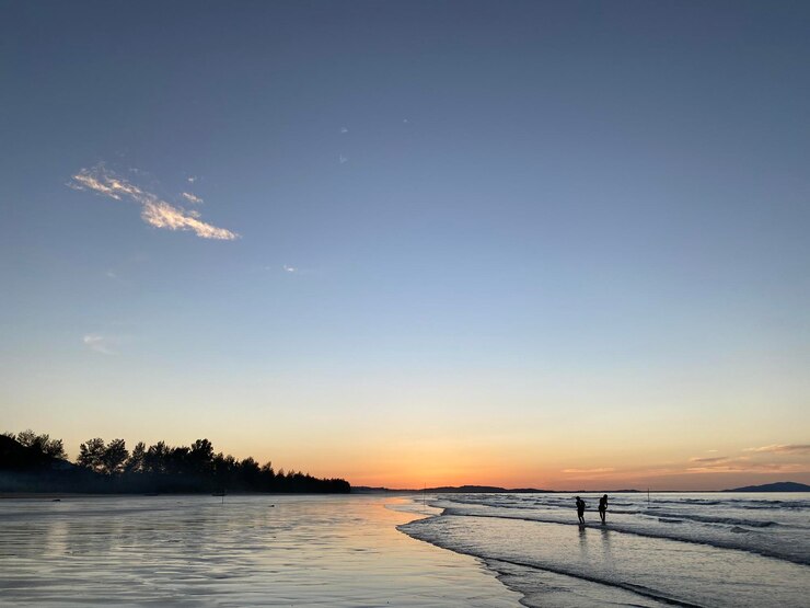 Photo 夕暮れの青い空の海辺の風景 夕暮れた青い空 青い砂の人々が歩いている