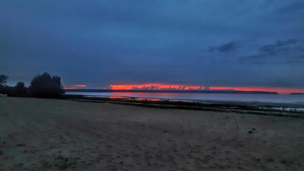 Scenic view of beach against sky at sunset