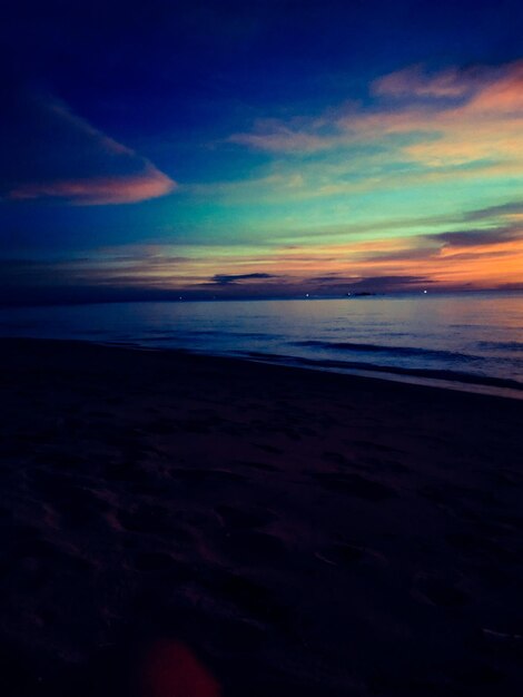 Scenic view of beach against sky at sunset