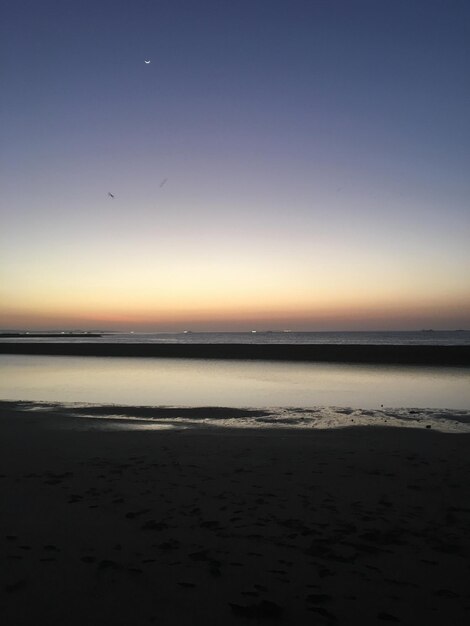 Scenic view of beach against sky at sunset