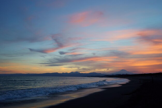 Scenic view of beach against sky at sunset