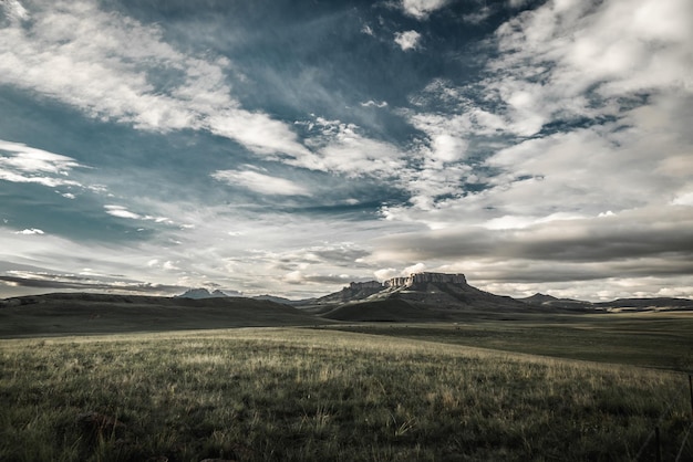 Scenic view of a beautiful field with large rocky mountains in the distance on a cloudy day