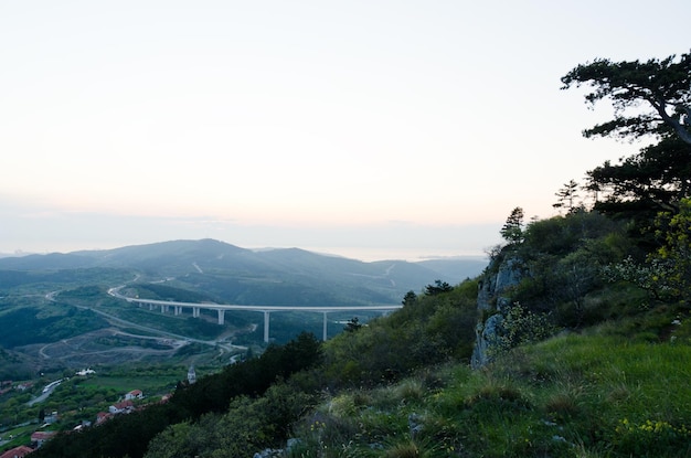 Scenic view. beautiful green hills, big bridge against red orange sky, spring. From Slovenia coast