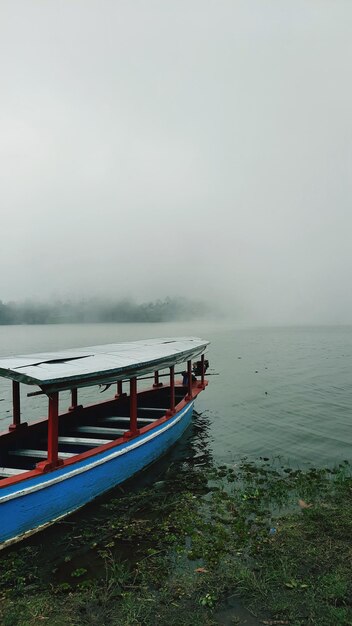 Photo scenic view of boat against foggy lake