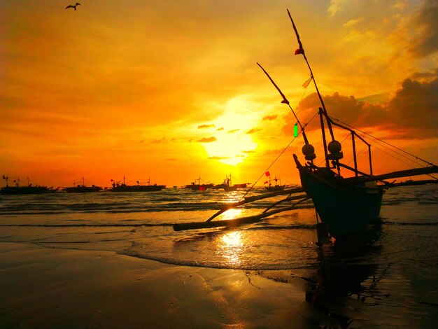 Scenic view of boat on beach at sunset