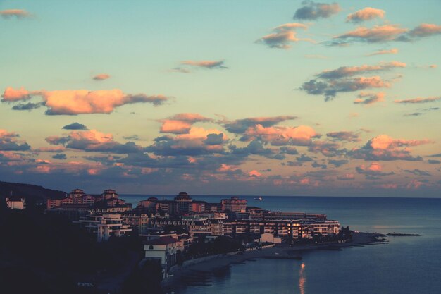 Scenic view of city by sea against sky during sunset