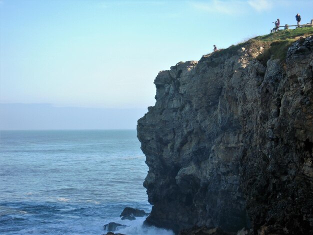 Scenic view of cliff by sea against clear sky