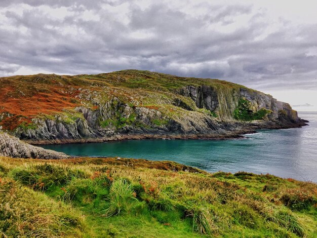 Photo scenic view of cliff by sea against sky