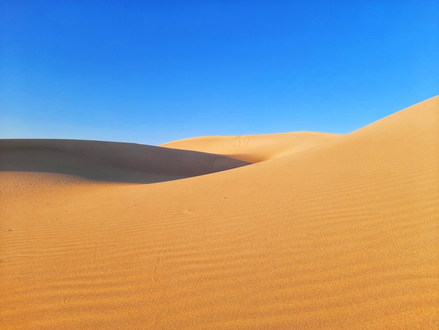 Scenic view of desert against clear blue sky