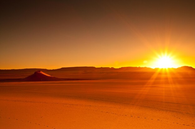 해가 지는 동안 하늘을 배경으로 사막의 경치