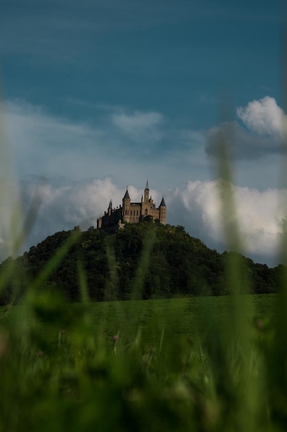 Photo scenic view of the field against the sky and a castle in the mountains