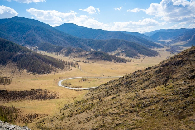 Scenic view from mountain pass to forest valley among mountain ranges and hills on horizon at change