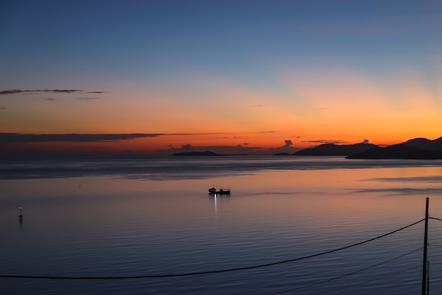 Vista panoramica dalla sagoma del peschereccio nell'oceano calmo durante l'alba