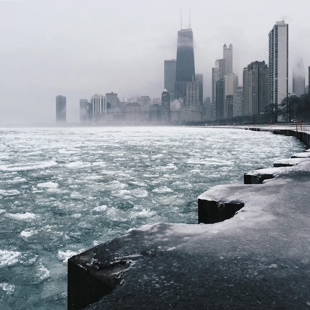Scenic view of frozen lake in city against sky during winter