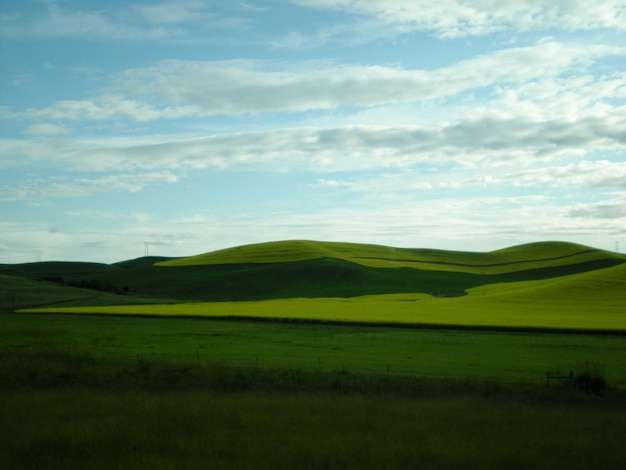 Scenic view of green hill against cloudy sky