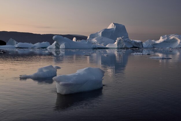 Photo scenic view of iceberg shapes and reflectins in mirror-like sea in greenland scoresby sound
