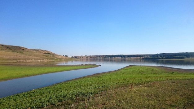 Scenic view of lake against clear blue sky