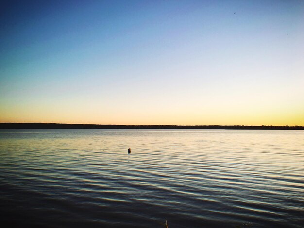 Scenic view of lake against clear sky during sunset