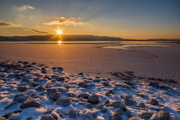 Scenic view of lake against cloudy sky during sunset