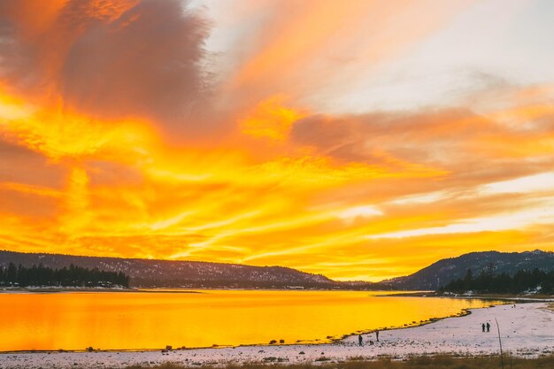 Scenic view of lake against dramatic sky during sunset