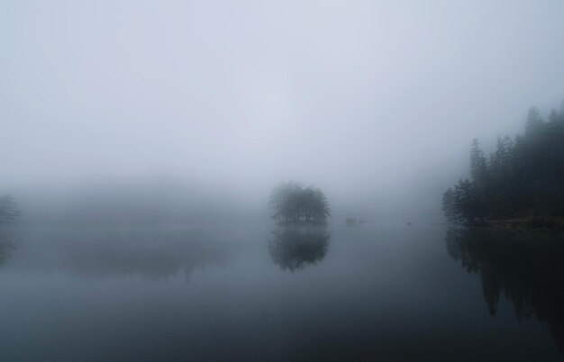 Scenic view of lake against sky at foggy weather