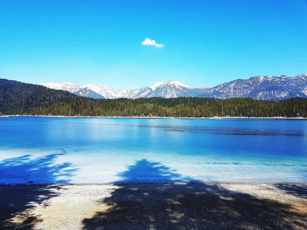 Scenic view of lake by mountains against blue sky