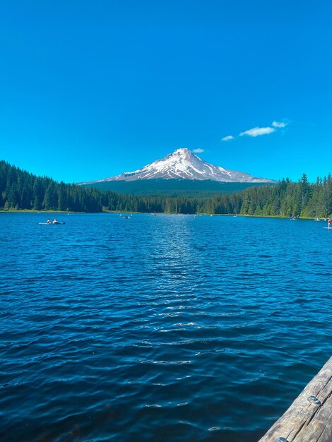 Scenic view of lake by mountains against clear blue sky